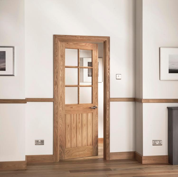 A picture of a glazed interior oak door in a home setting with modern door furniture.