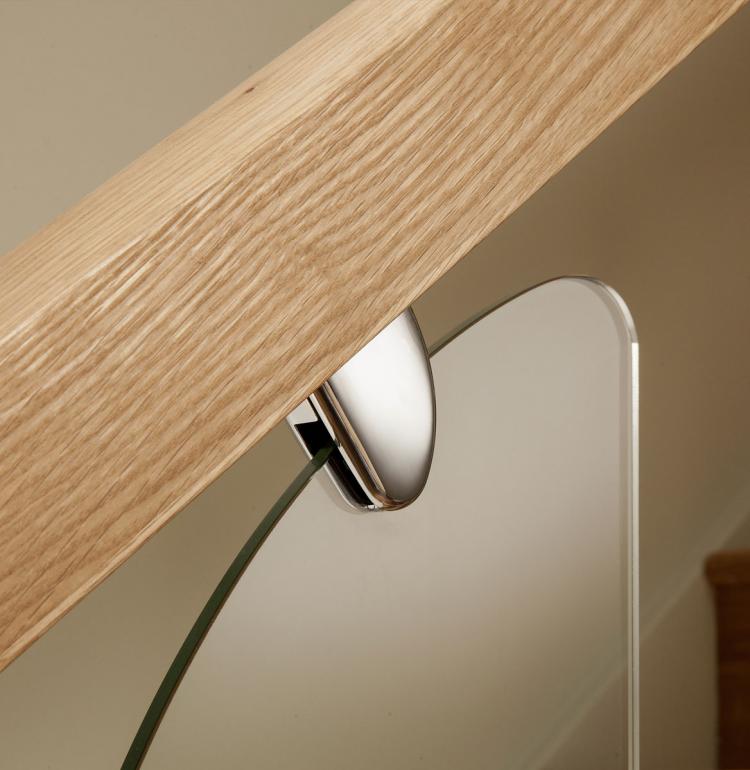 A picture of a stainless steel glass clamp, clear glass panel and solid oak handrail.